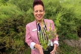 woman in pink jacket holds a pot plant