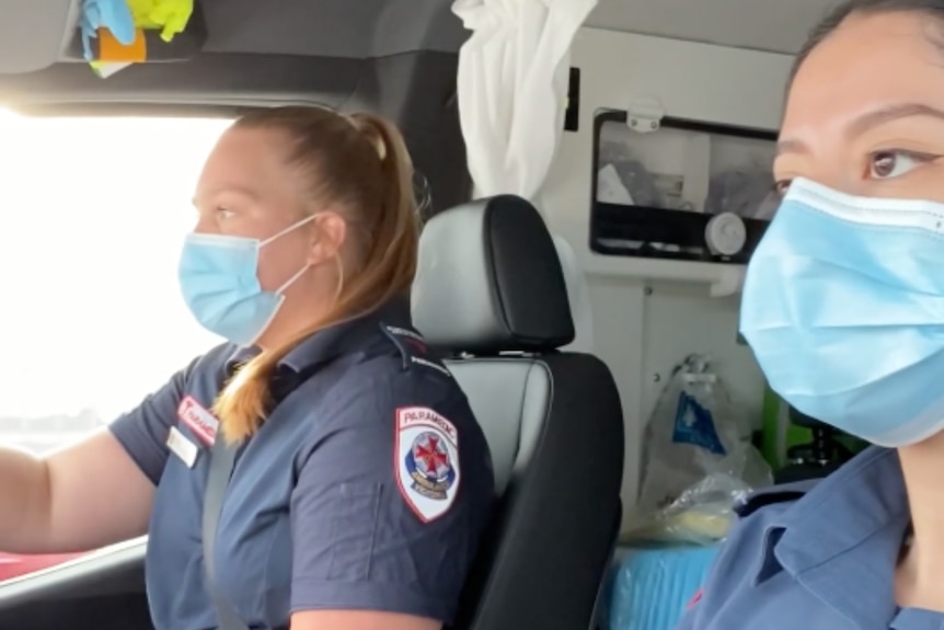 Two female paramedics driving ambulance wearing masks