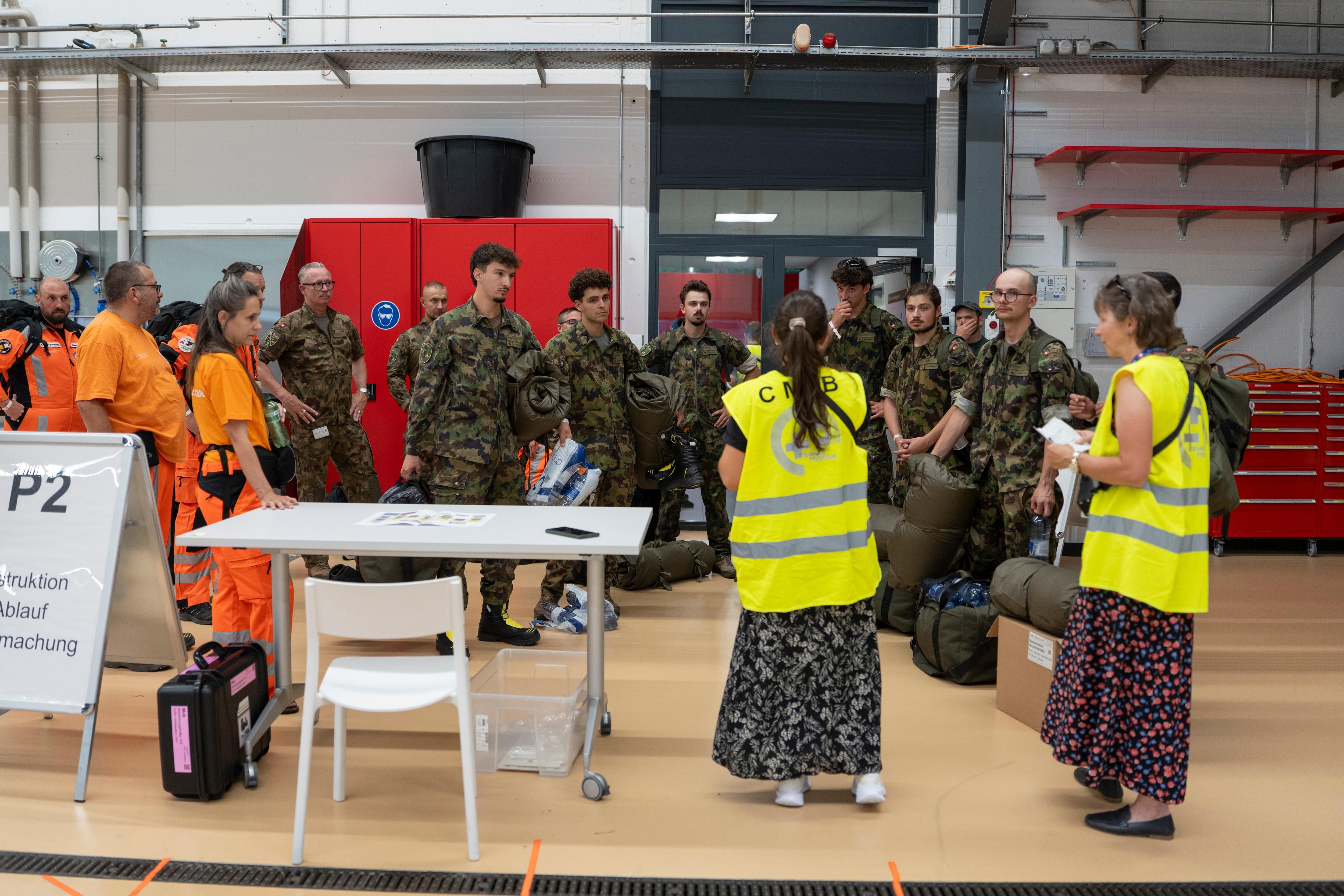 army members stand being spoken to by women in high vis vests