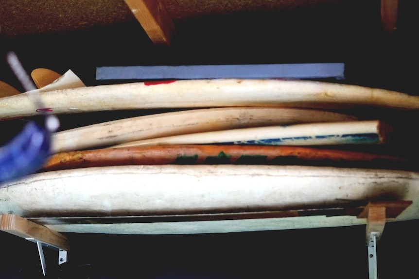 Several unpainted surfboards piled up on the wall of Jeremy's shed
