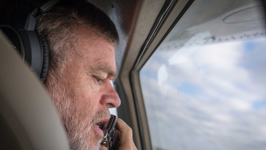 A pensive Professor Richard Kingsford sitting in a light aircraft using a voice recorder to log bird citings, 2016.