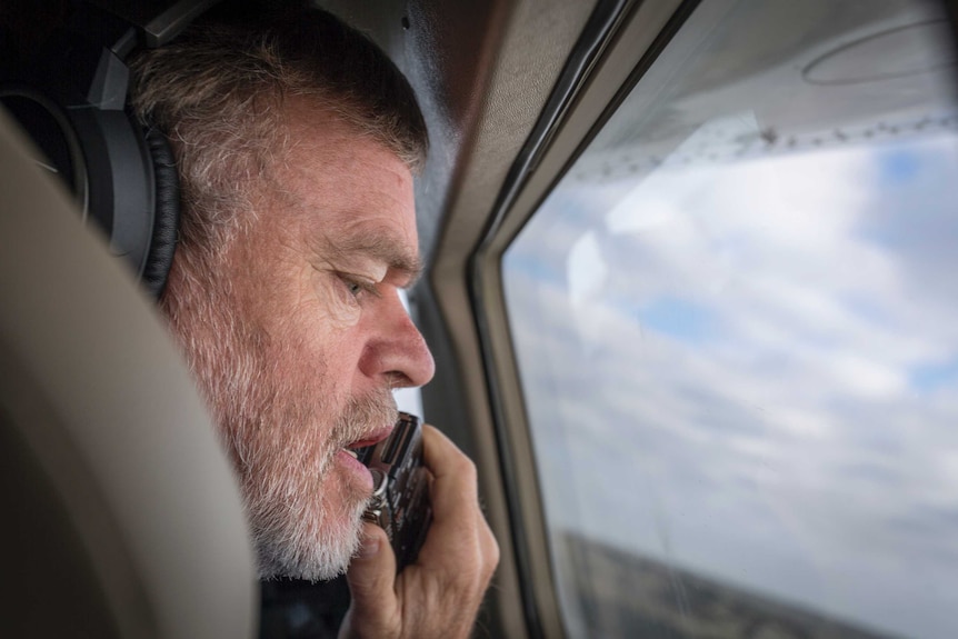 A pensive Professor Richard Kingsford sitting in a light aircraft using a voice recorder to log bird citings, 2016.