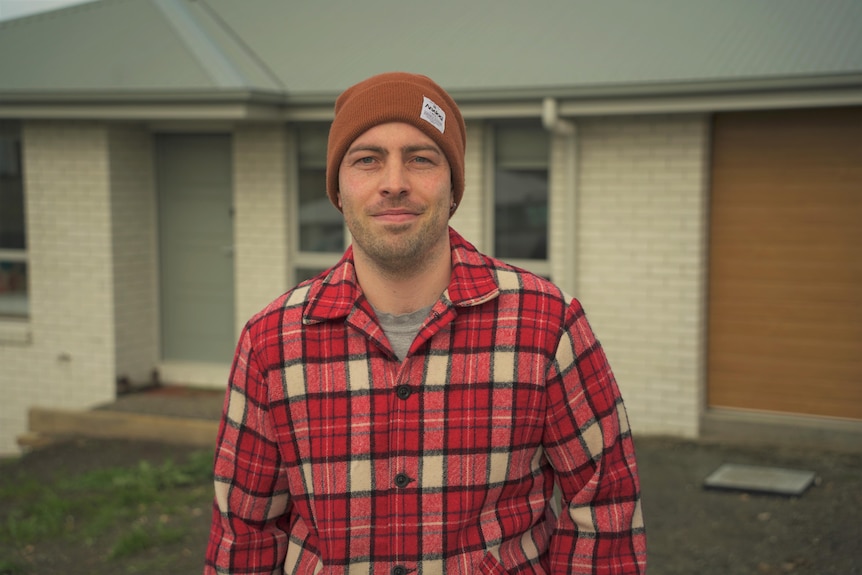 A man in a beanie smiles at the camera