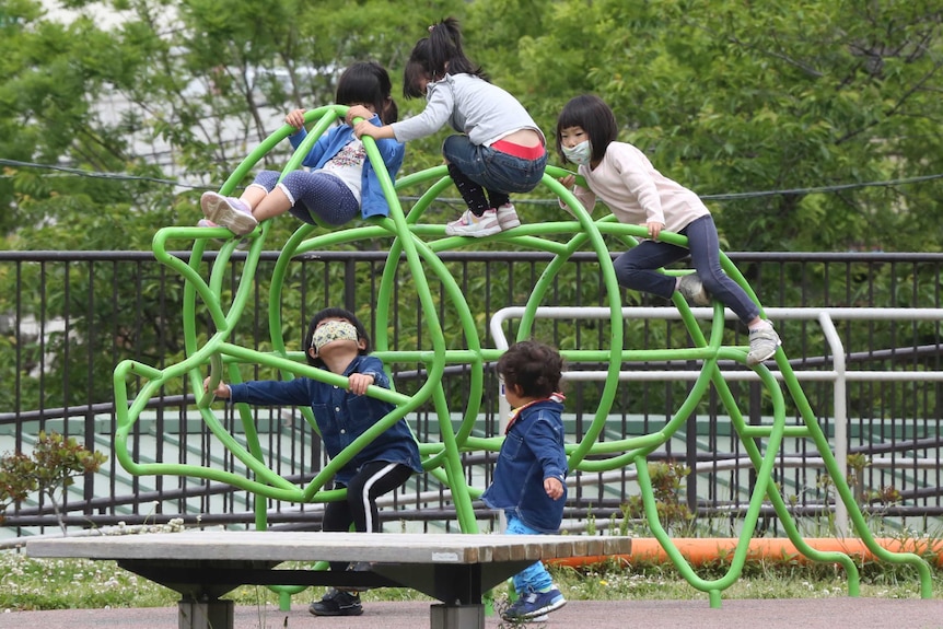 Kids in face masks climb over playground equipment