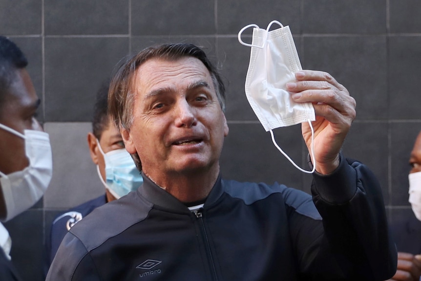 Brazil's President Jair Bolsonaro holds a face mask as he leaves Vila Nova Star Hospital.