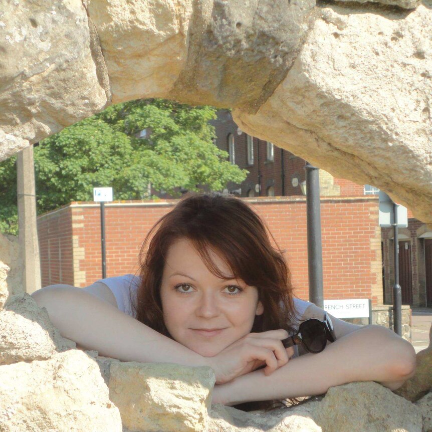 Yulia Skripal smiles while looking though hole in rock formation