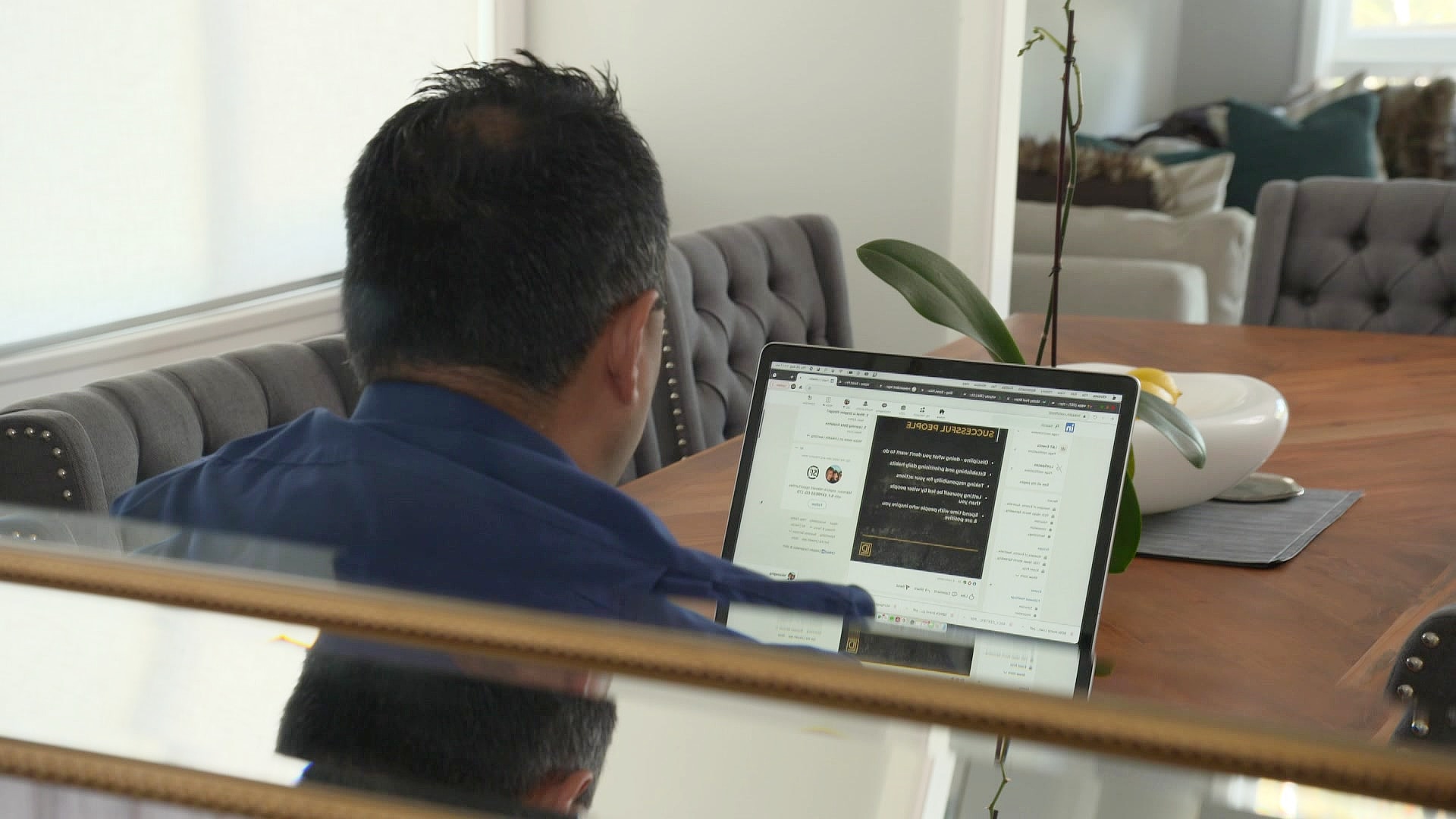 a man sitting behind a computer at a dining room table at home