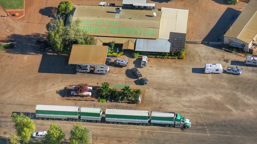 An aerial view of a remote roadhouse between the Northern Territory and Queensland with trucks outside.