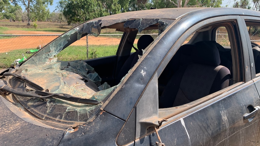 A car that has smashed out windows and a burnt body.