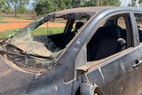 A car that has smashed out windows and a burnt body.