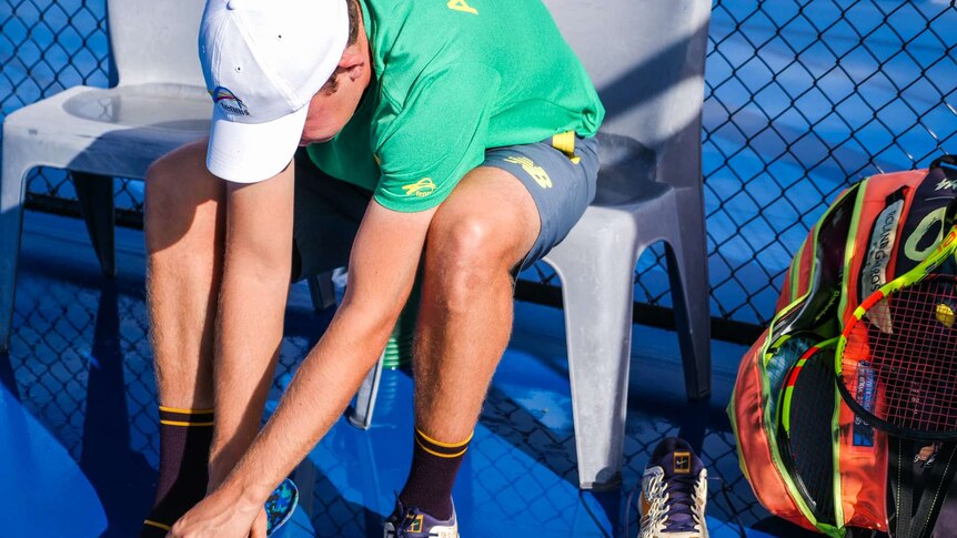 Tennis player putting on his shoes.