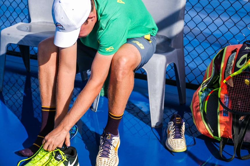 Tennis player putting on his shoes.