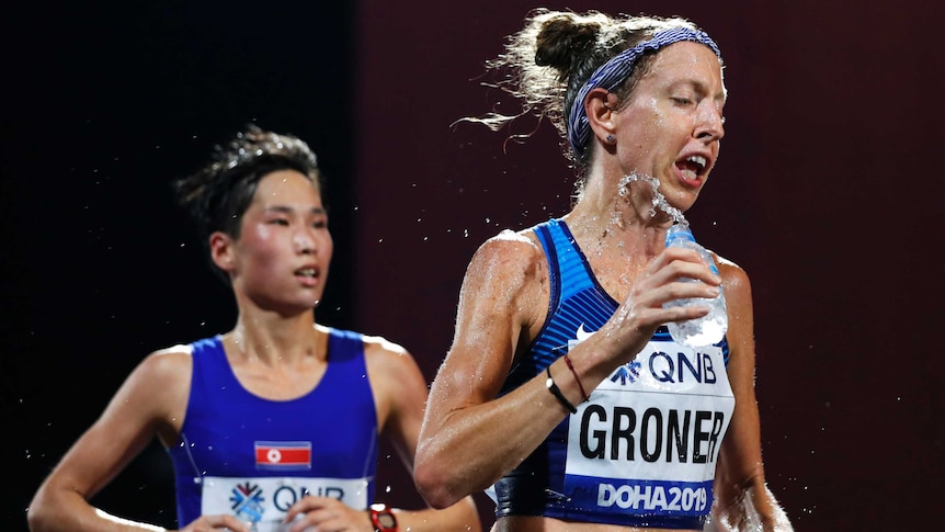 A runner splashes water from a bottle on her face and neck as she competes in a marathon.