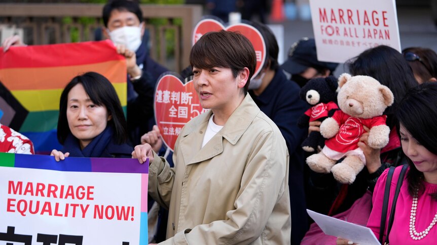 A group of Japanese men and women gather outside a court in Tokyo displaying messages of support for marriage equality.