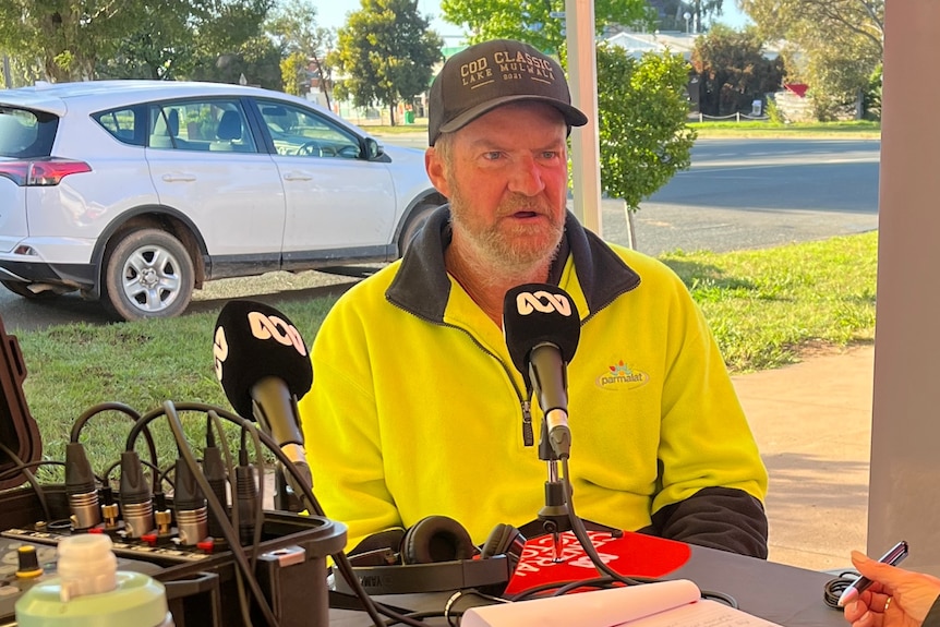 A man in hi-vis speaks into a microphone.