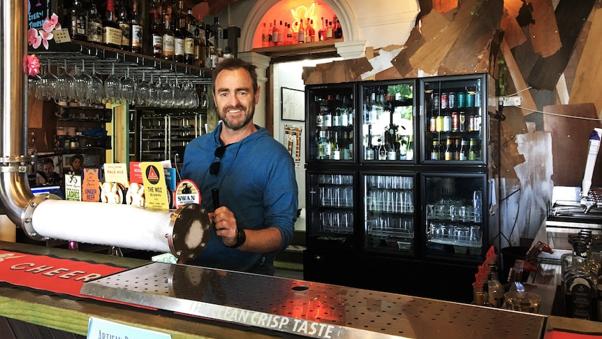 man stands behind a bar 