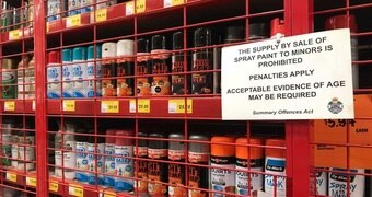 Spray paint cans behind a cage at a hardware store in Brisbane.