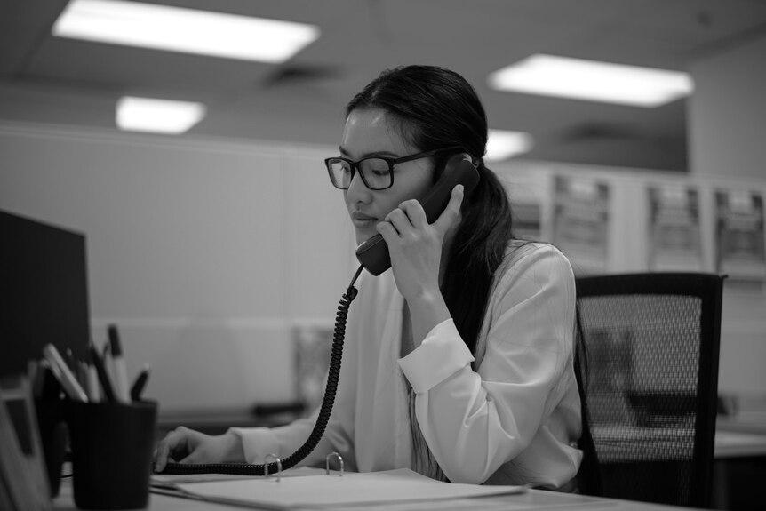 A frontline domestic violence worker speaks on a desk phone