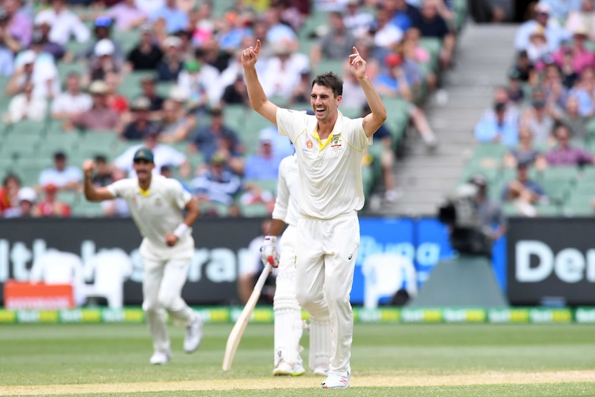 Pat Cummins raises his arms in celebration as Cheteshwar Pujara walks off after his dismissal