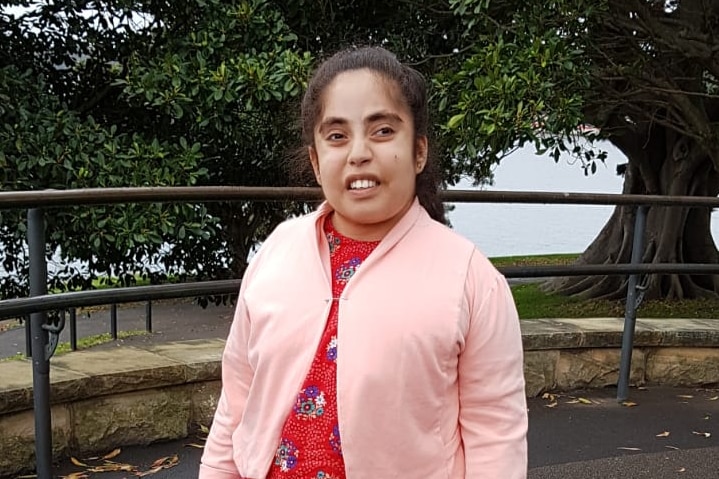 A woman wearing a pink cardigan smiles