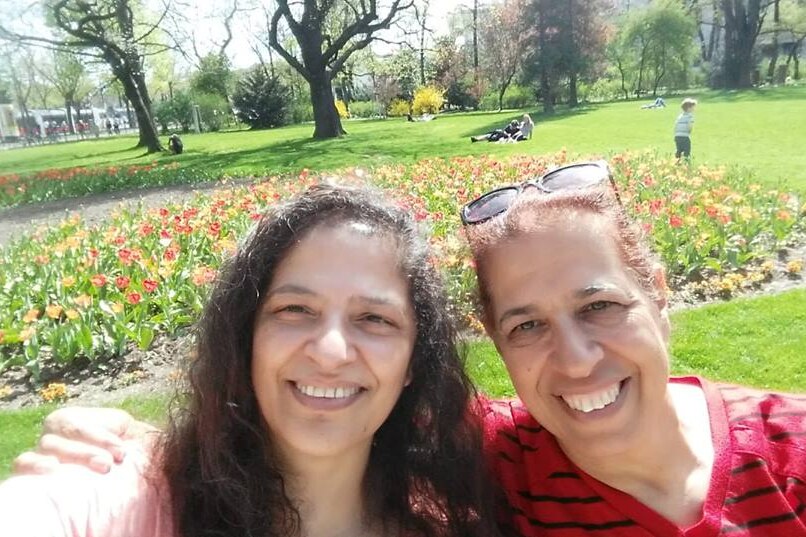 Two women smile at the camera in a selfie taken in a park.