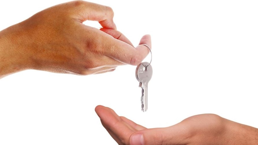 Photo of one hand giving a key to another hand 