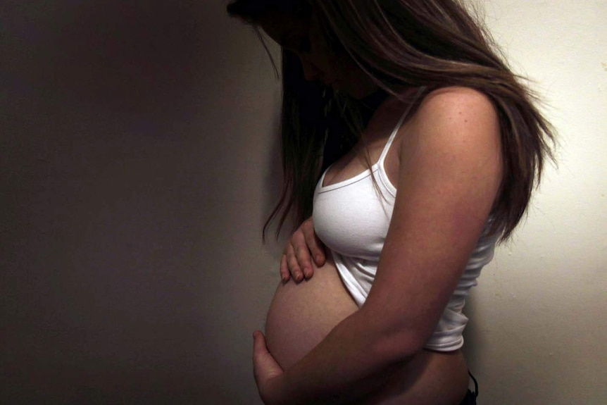 An unidentified pregnant woman holds her belly.