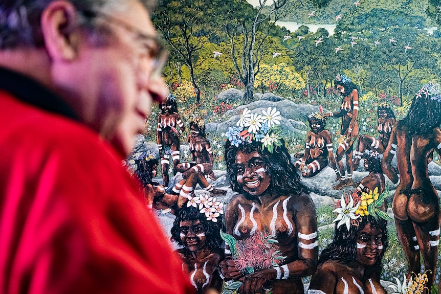 Danny Eastwood with a painting of Indigenous women in the Australian bush.