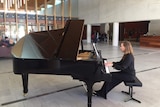 Katherine Day sits at a piano at the gallery.