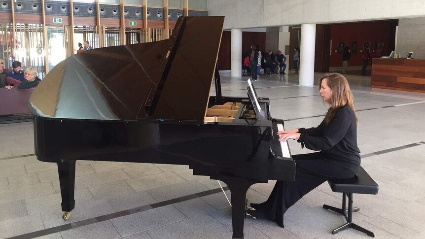 Katherine Day sits at a piano at the gallery.
