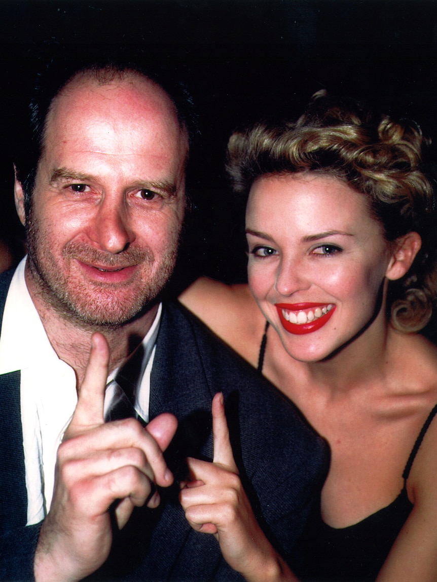 Michael Gudinski and Kylie Minogue hug and point their fingers up