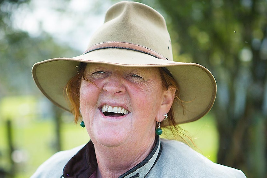 A woman, with a big smile, wearing a hat