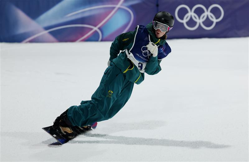 Un snowboarder con equipo verde y un casco se desliza sobre la nieve.