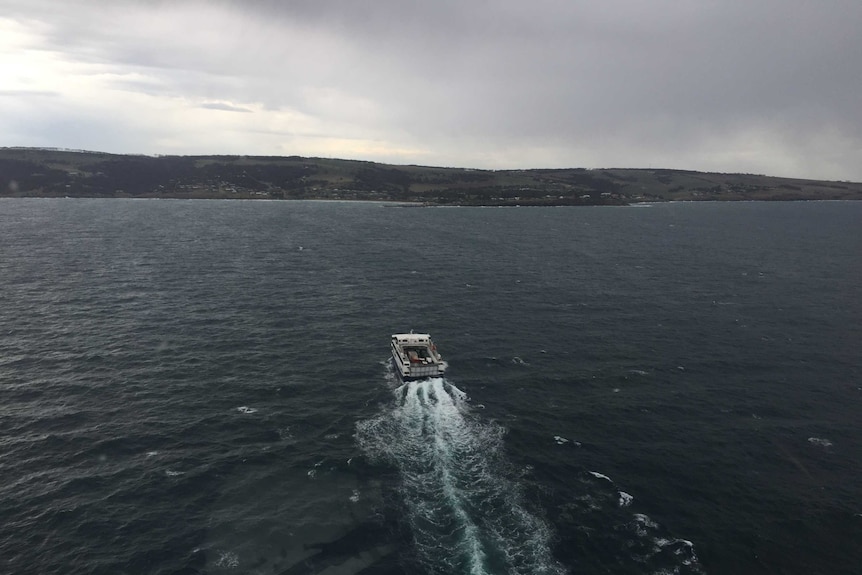 A ferry travelling towards an island with dark cloudy skies ahead