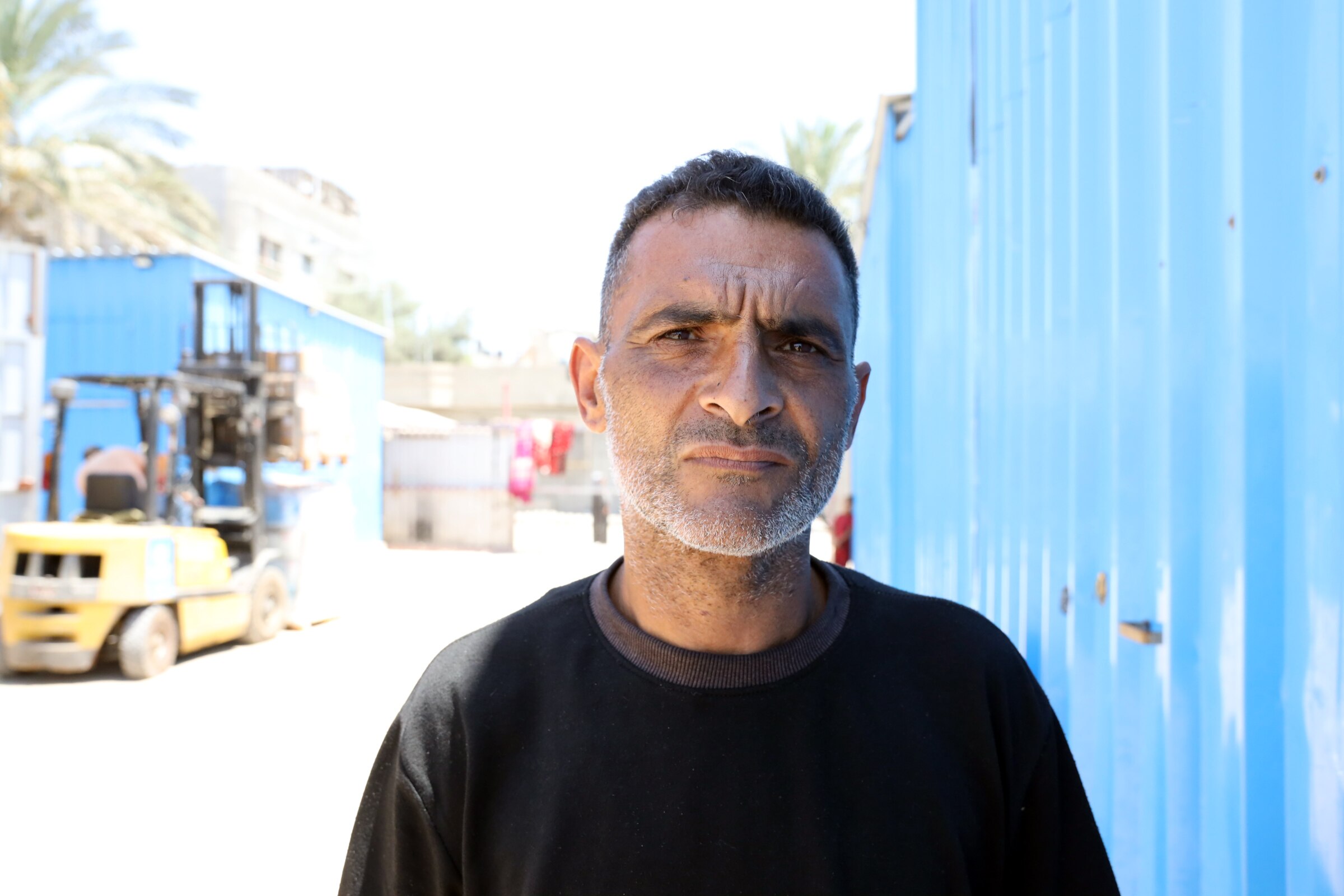Rami Jaber Nawfal stands near a blue shipping container and looks into the camera.
