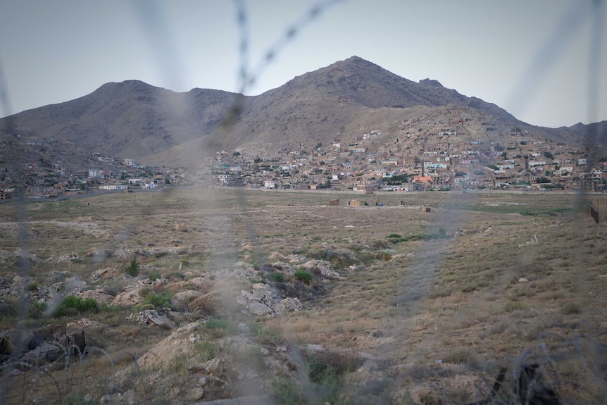 Mountains around Kabul seen from a distance through barbed wire.