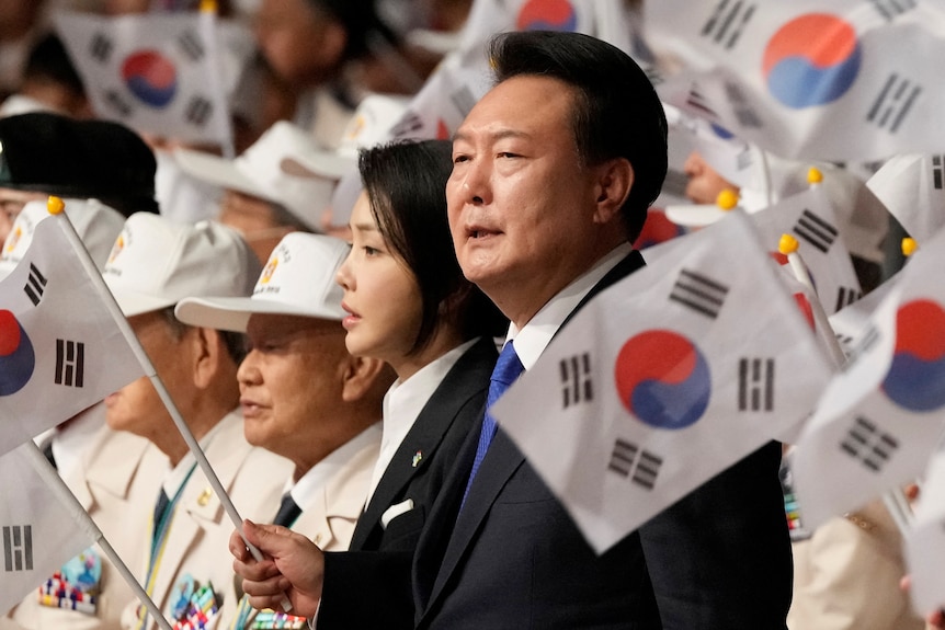 A man in suit waving South Korean national flag. 