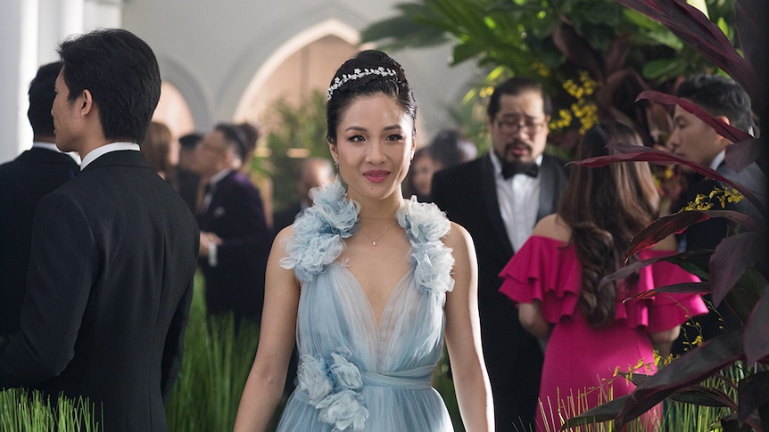 Colour still of Constance Wu slightly smiling and wearing a light blue chiffon dress in 2018 film Crazy Rich Asians.