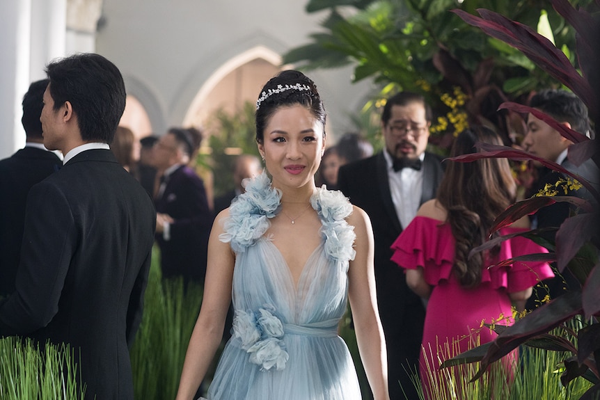 Colour still of Constance Wu slightly smiling and wearing a light blue chiffon dress in 2018 film Crazy Rich Asians.