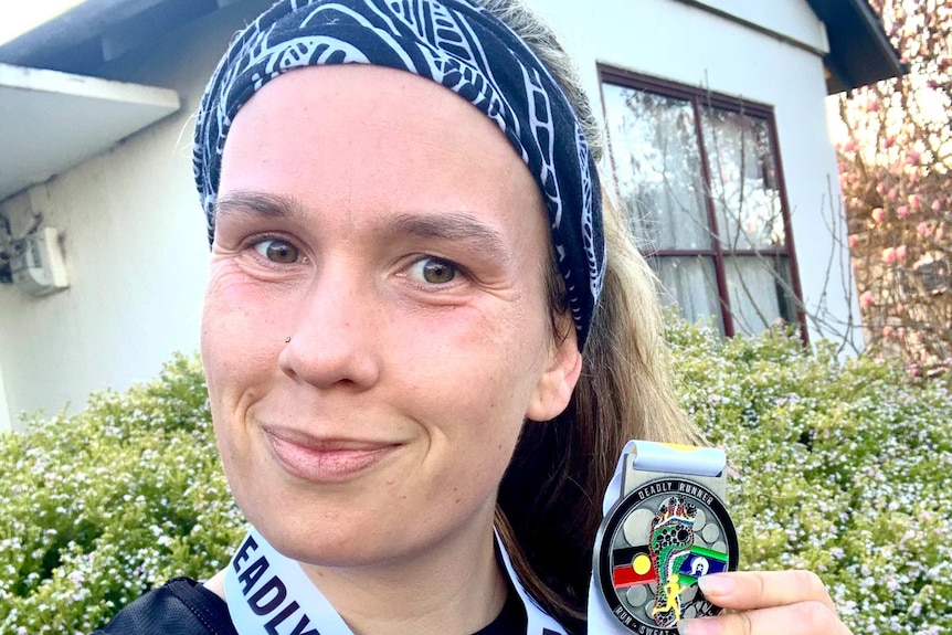 Woman holding up running medal