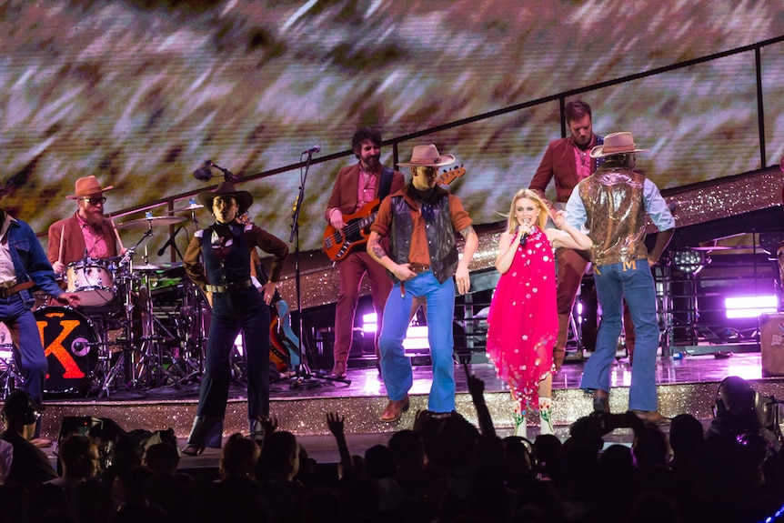 Kylie Minogue stands in line with her cowboy-dressed dancers