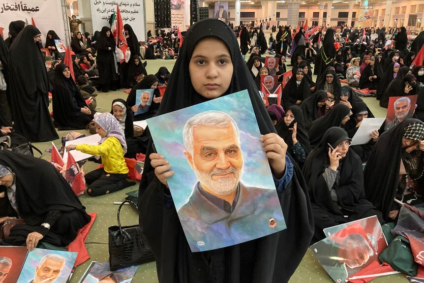 Girl wearing a black chador holds a poster of the late Revolutionary Guard Gen. Qassem Soleimani