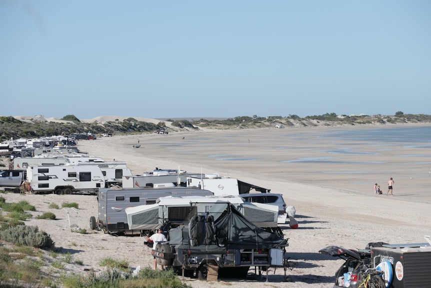 White sandy beach, caravans, water, people, sand dunes 