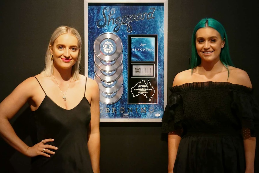 Two ladies standing by a poster.