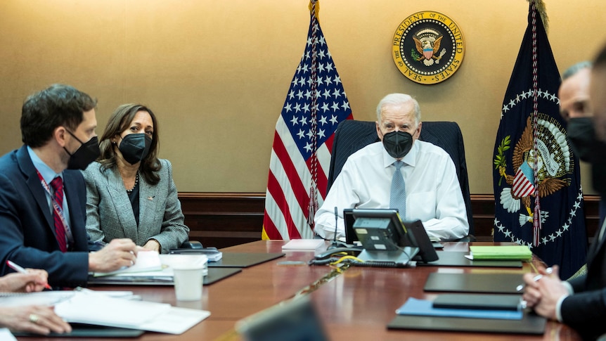 U.S. President Joe Biden and other White House national security staff sit at a table.