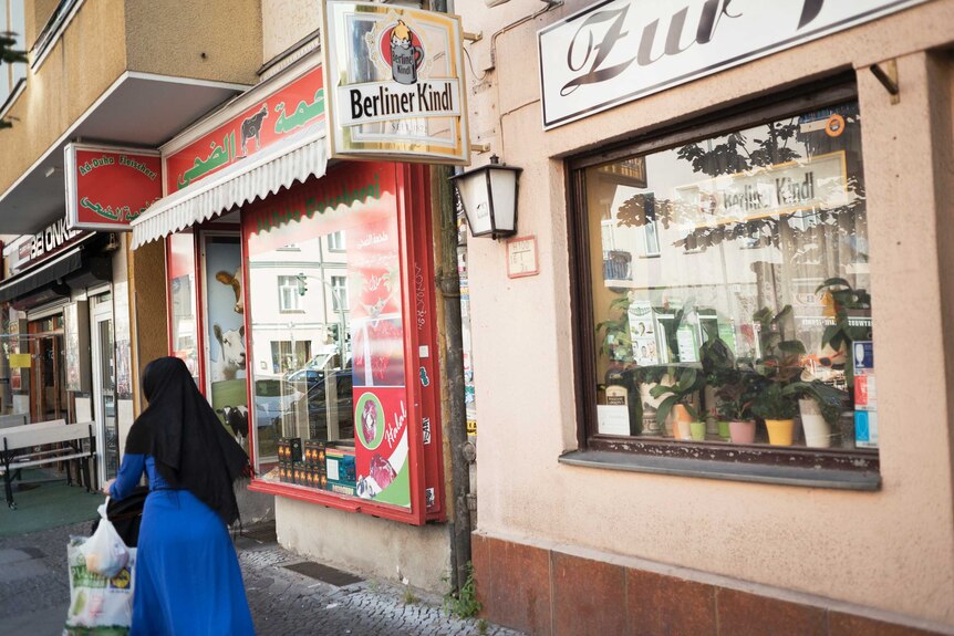 A woman in a hijjab walks past shops.