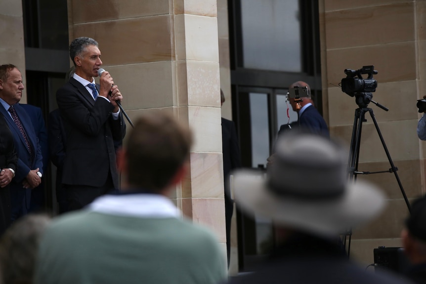 Tony Buti wears a suit as he addresses a rally on the steps of WA Parliament