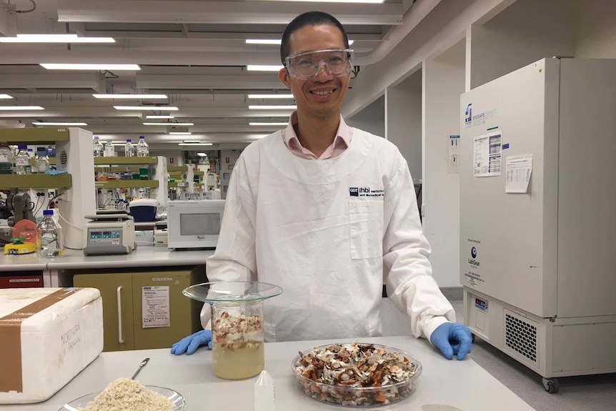 Dr Phong Tran standing in a lab with a bowl of prawn shells.