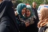 Two women embrace crying at a funeral in Gaza. 
