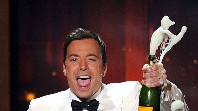 Host Jimmy Fallon holds a bottle of champagne